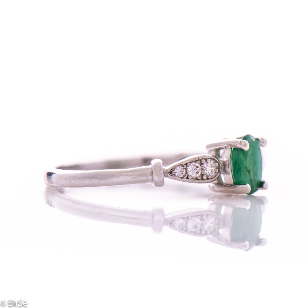 An elegant women's ring with a modern design of the detail and extraordinary craftsmanship entirely of rhodium-plated silver, complemented by the glow of natural emerald stone and fine zircons. In an exclusive sterling silver set with earrings and pendant