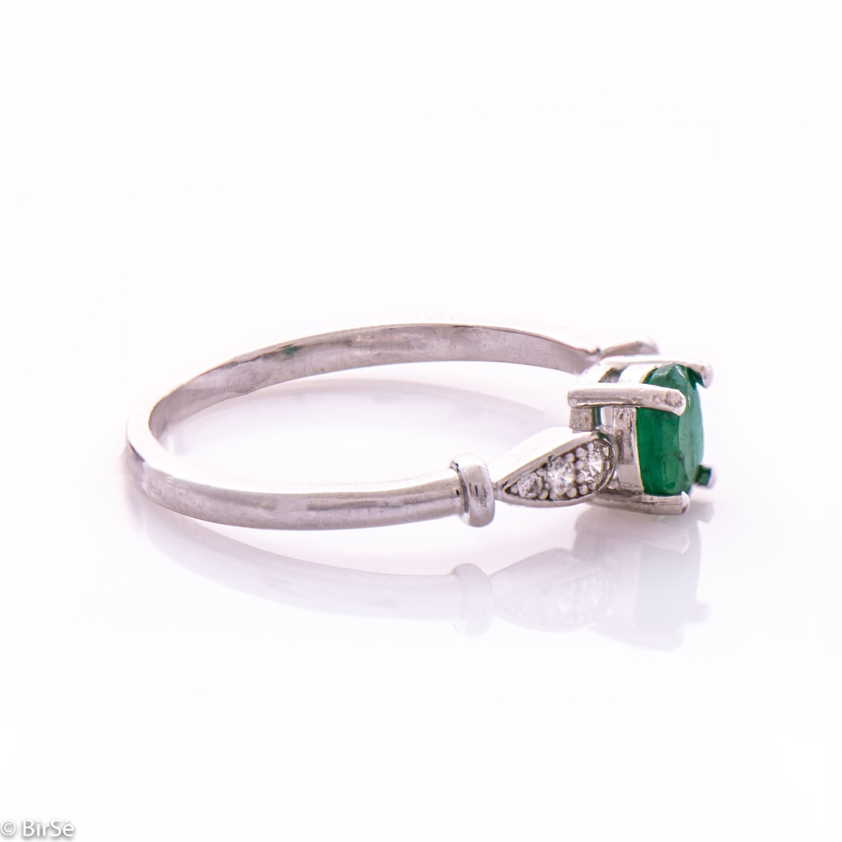 An elegant women's ring with a modern design of the detail and extraordinary craftsmanship entirely of rhodium-plated silver, complemented by the glow of natural emerald stone and fine zircons. In an exclusive sterling silver set with earrings and pendant