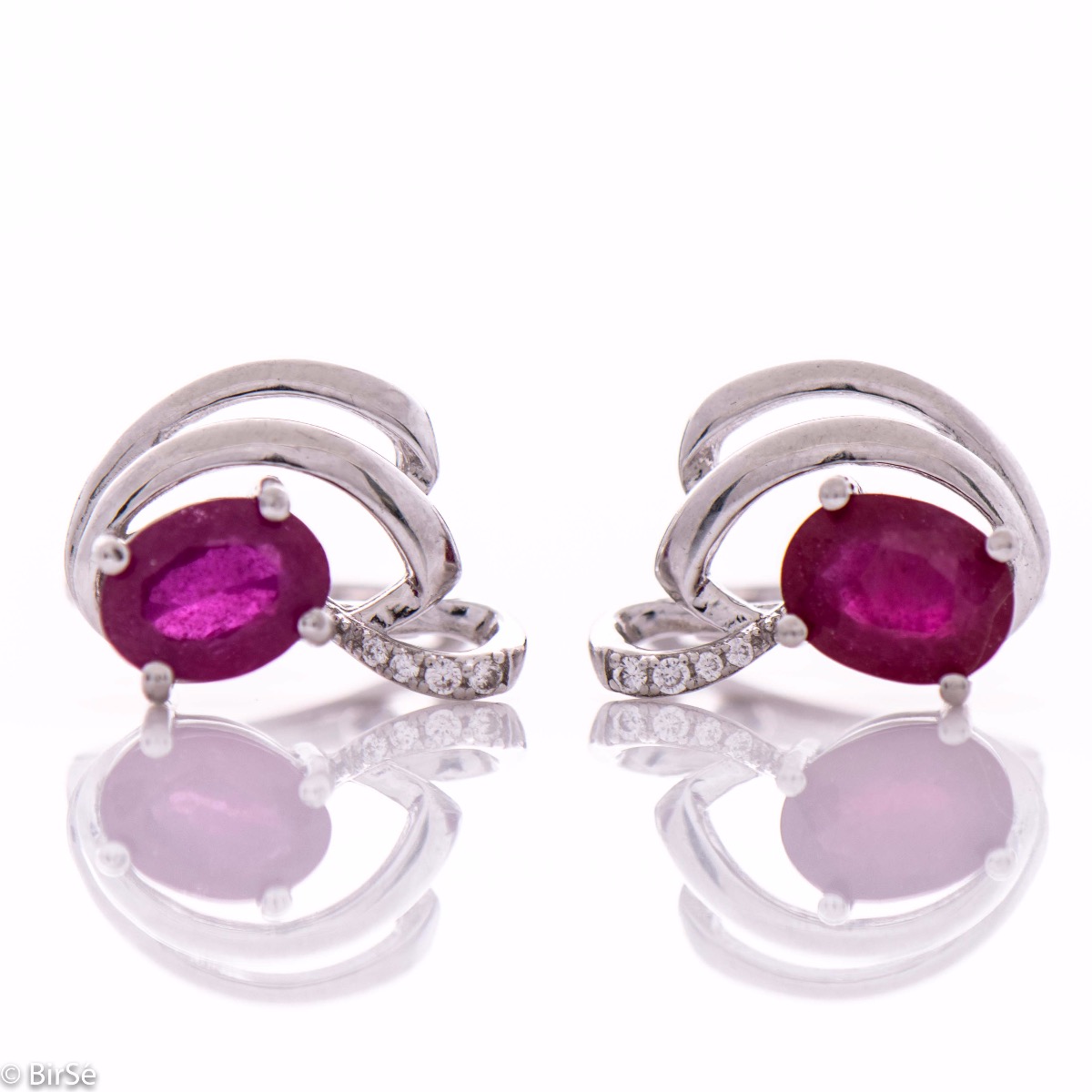 Sophisticated women's earrings with a non-standard and modern design, made entirely of beautiful rhodium-plated silver, complemented by a radiant natural ruby ​​stone and delicate zircons. In an exclusive sterling silver pendant and ring set.