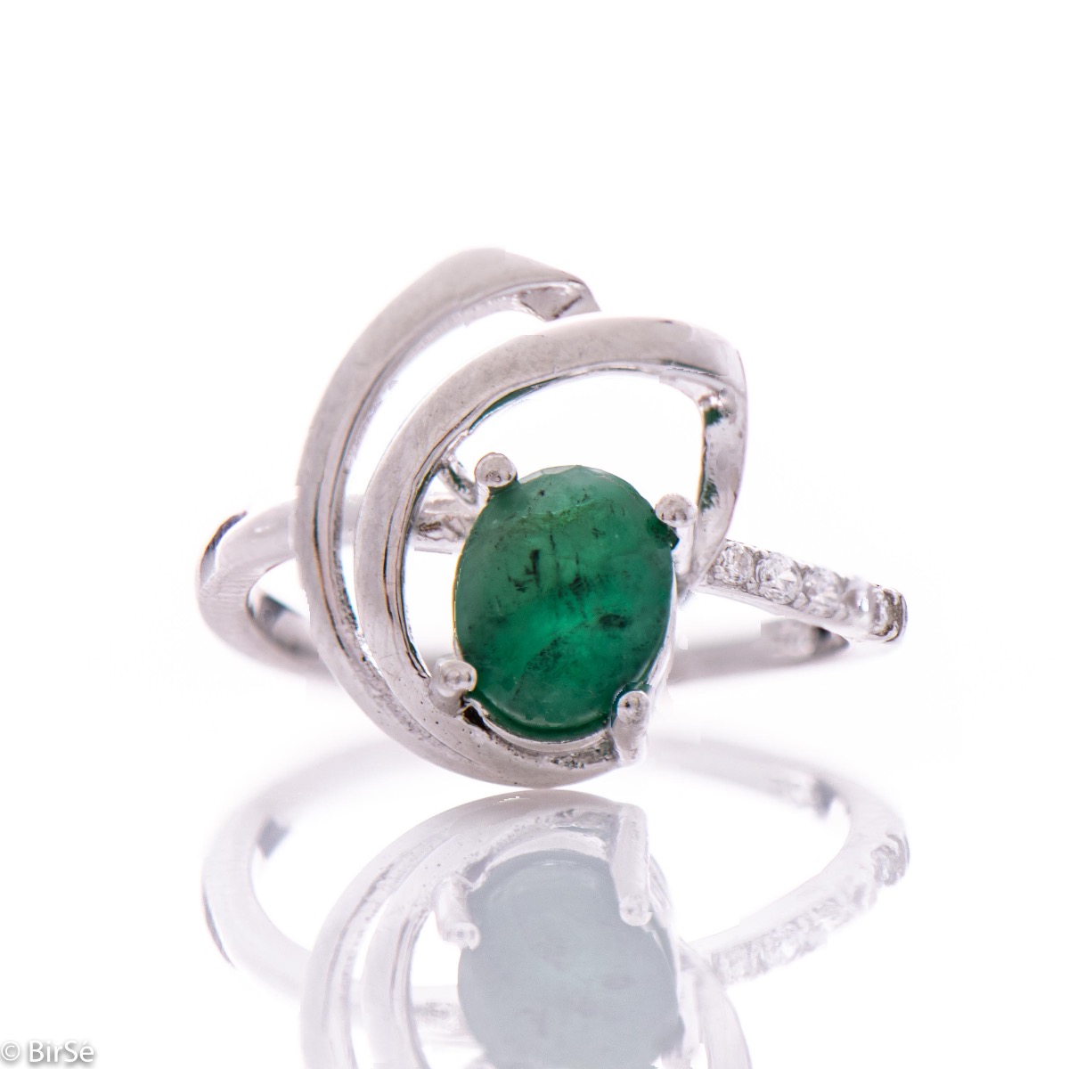 An elegant women's ring with a radiant natural emerald, complemented by sparkling zircons and sophisticated and spectacular craftsmanship entirely in beautiful rhodium-plated silver. In an exclusive set with a pendant and earrings.