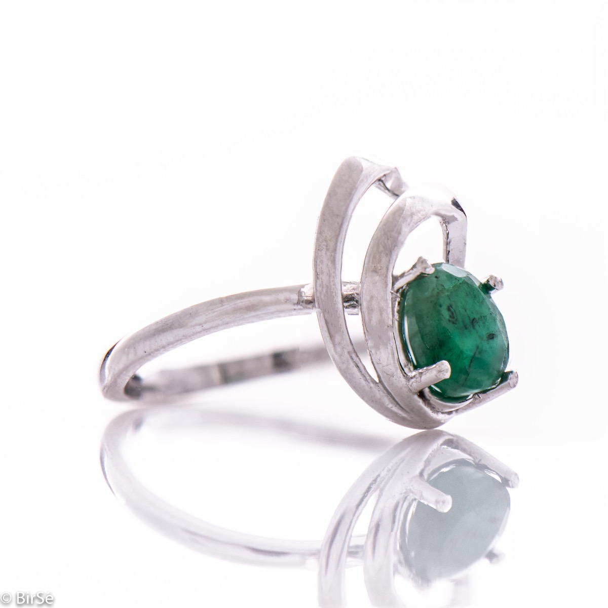 An elegant women's ring with a radiant natural emerald, complemented by sparkling zircons and sophisticated and spectacular craftsmanship entirely in beautiful rhodium-plated silver. In an exclusive set with a pendant and earrings.