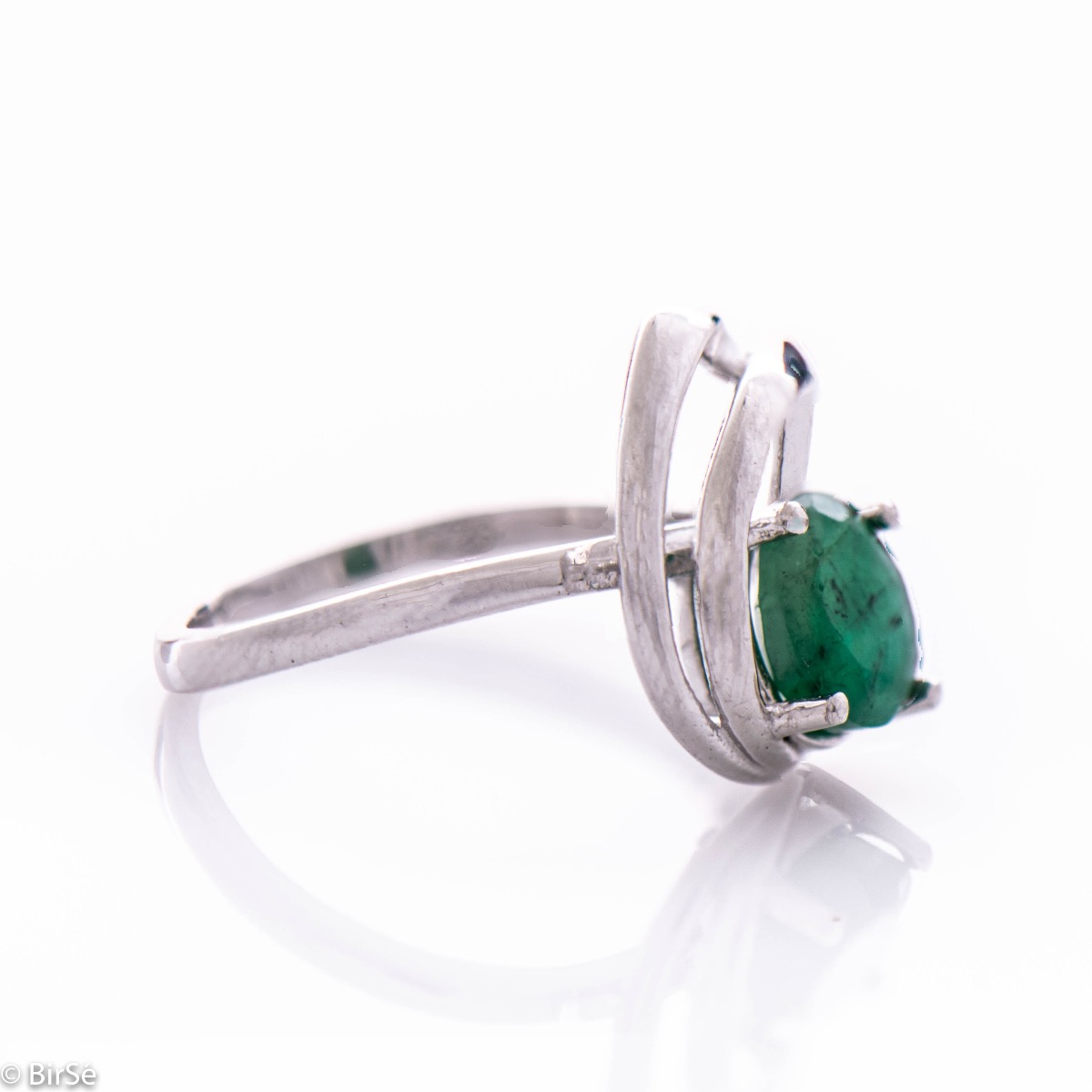 An elegant women's ring with a radiant natural emerald, complemented by sparkling zircons and sophisticated and spectacular craftsmanship entirely in beautiful rhodium-plated silver. In an exclusive set with a pendant and earrings.