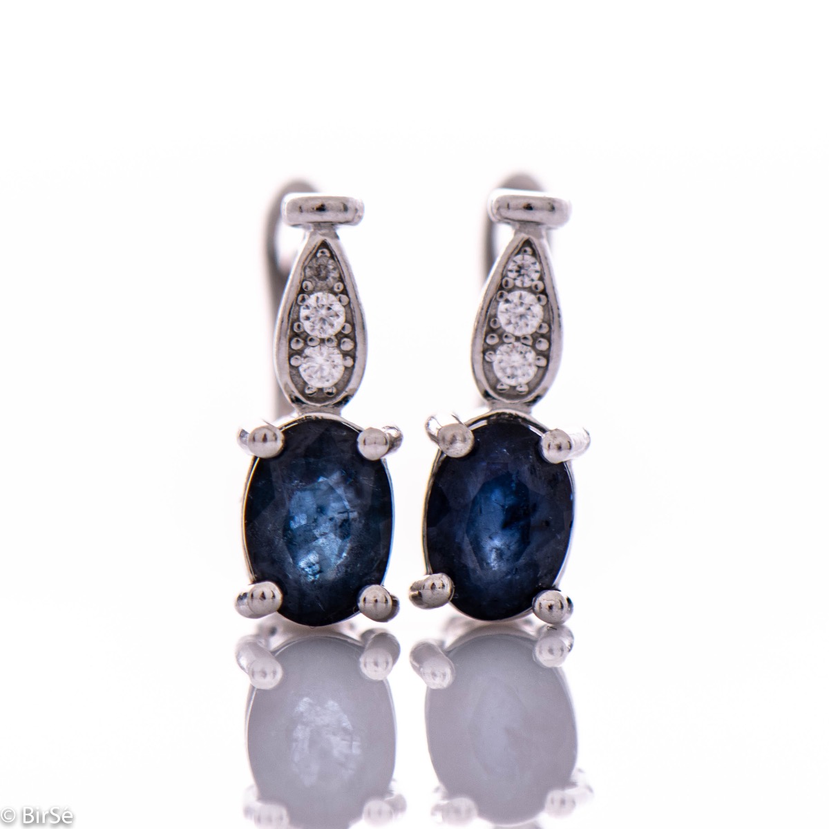 Fine ladies earrings with English clasp and delicate intertwining of radiant natural sapphire with sparkling zircons and exquisite craftsmanship of beautiful rhodium silver. In an exclusive ring and pendant set.