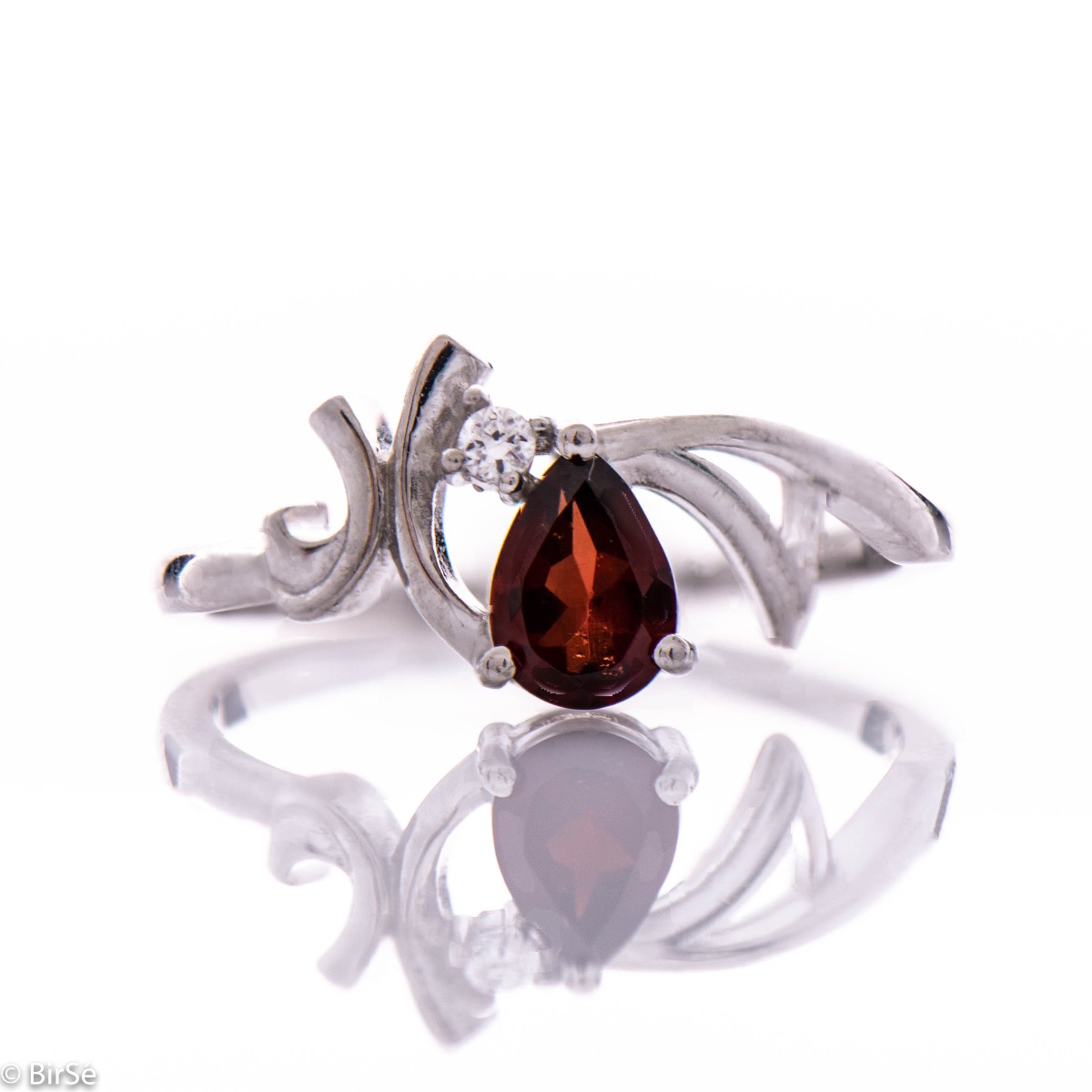 Elegant ladies' ring with subtle curves and made entirely of beautiful rhodium-plated silver, complemented by a radiant natural garnet, in a delicate teardrop shape and a fine zircon. In an exclusive set with a pendant and earrings.