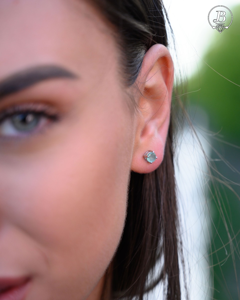 Delicate and radiant stud earrings exquisitely crafted entirely from rhodium-plated silver, delicately intertwined with the luster of a natural emerald stone.