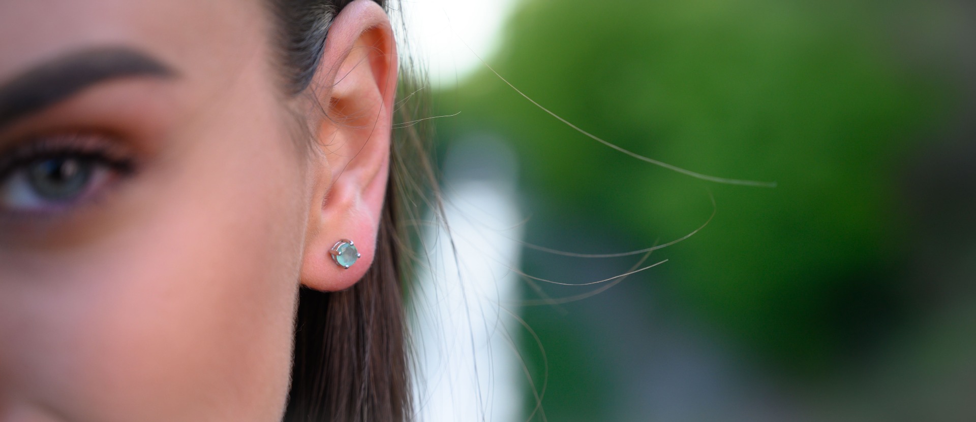 Delicate and radiant stud earrings exquisitely crafted entirely from rhodium-plated silver, delicately intertwined with the luster of a natural emerald stone.