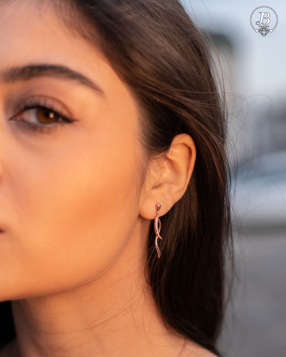 Charming women's dangle earrings made entirely of soft rose silver with exquisitely shaped curves, embellished with dazzling cubic zirconias. Fastening with a pin is for more convenience and comfort.