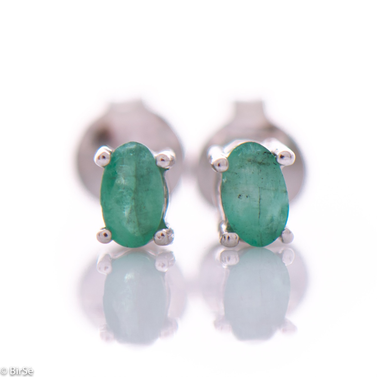 Delicate and spectacular stud earrings of beautiful rhodium silver intertwined with the glow of a natural emerald.