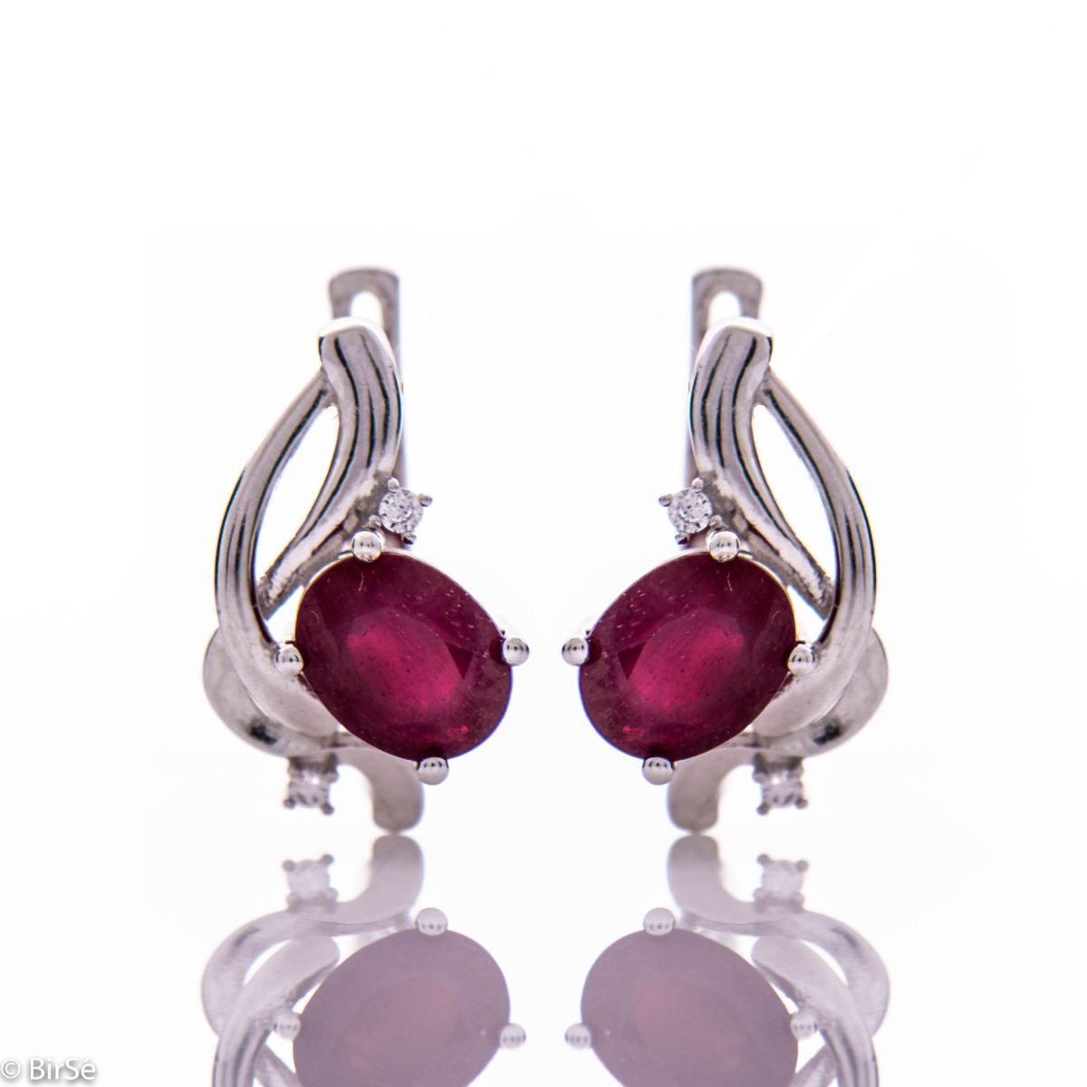 Delicate and elegant earrings in fine rhodium silver, charmingly intertwined with radiant natural ruby ​​and zircons.