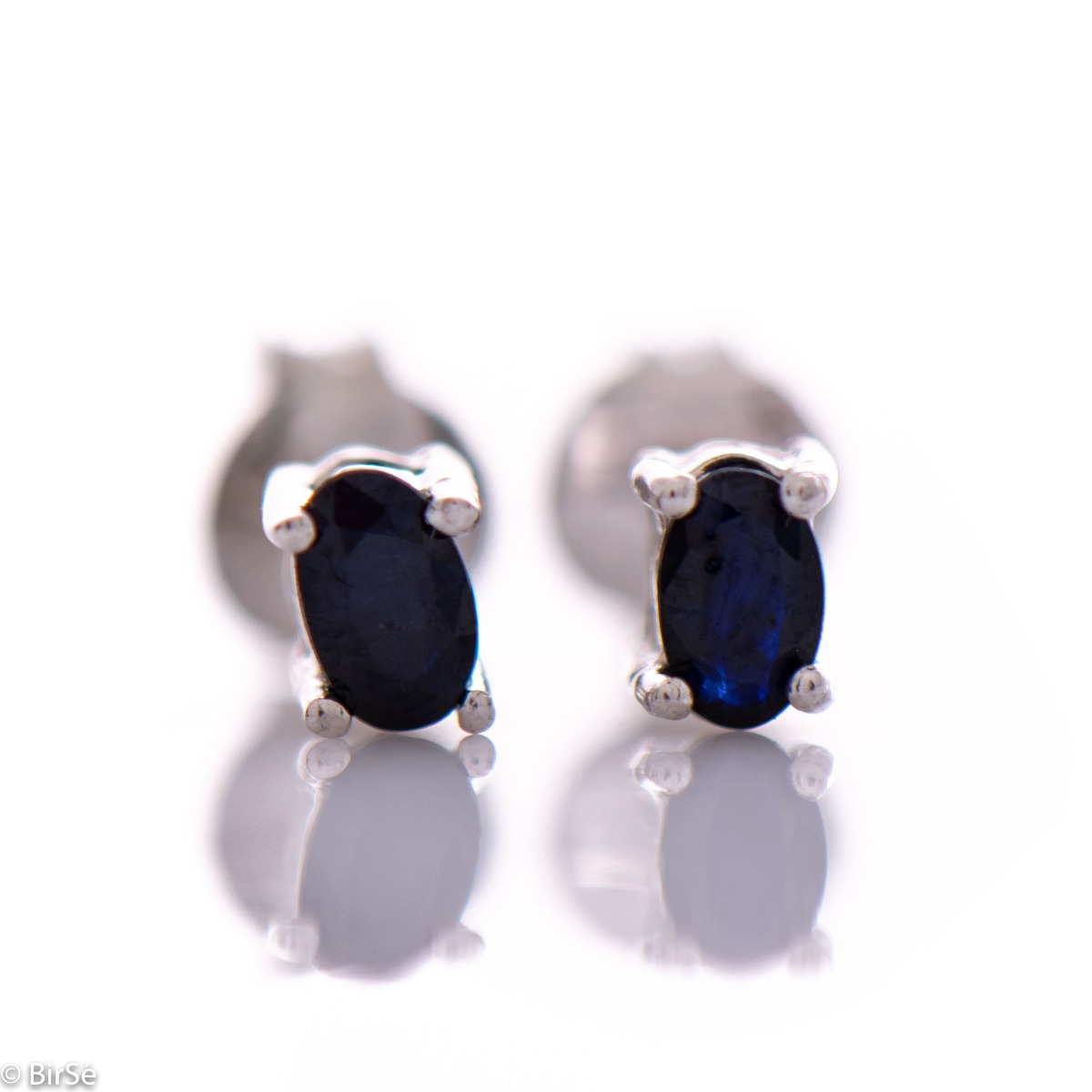 Extremely fine women's earrings in delicate rhodium silver on a stud, complemented by the brilliance of a natural sapphire.