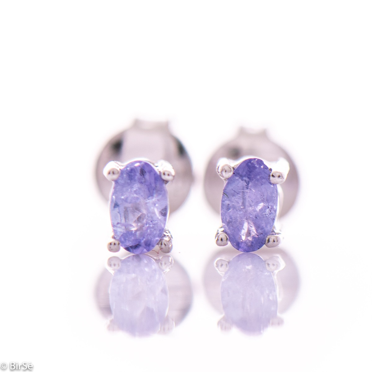 Fine and delicate stud earrings in rhodium silver with the gentle glow of natural tanzanite.