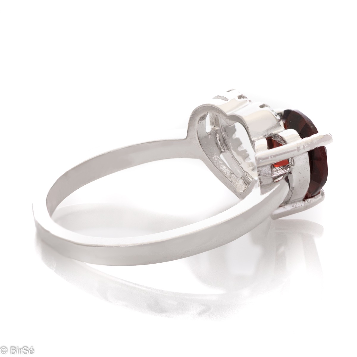 A spectacular ring made of a fine combination of rhodium-plated silver and stunning cubic zirconia stones, elegantly covering a beautiful heart. An enchanted natural garnet stone is gently nestled against the heart. The jewel is part of a set of dangling 