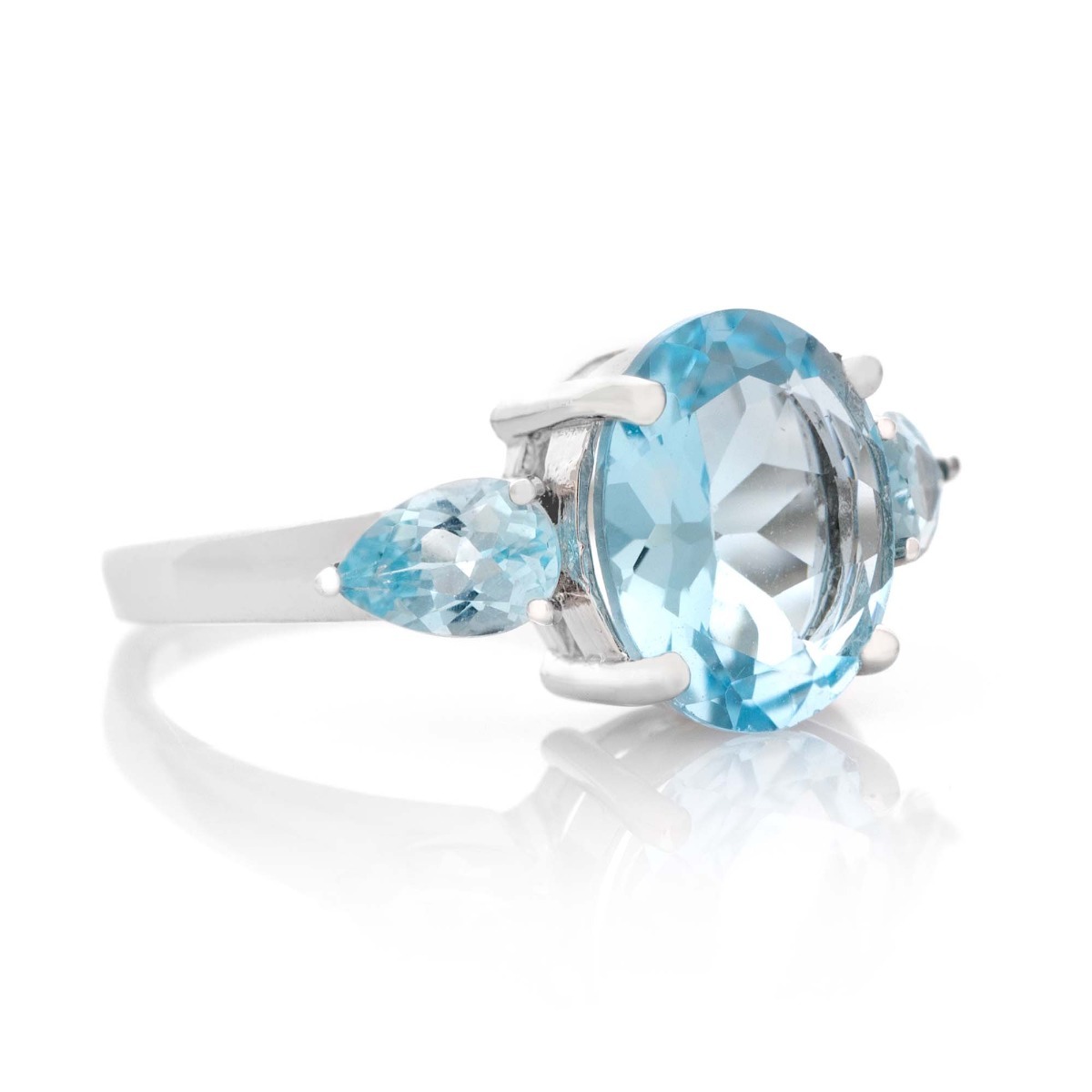 An alluring ladies' ring crafted from delicately rhodium-plated silver that elegantly holds a delightful natural blue topaz. The ring is part of a lovely set that includes dangling earrings and a sky blue topaz pendant.