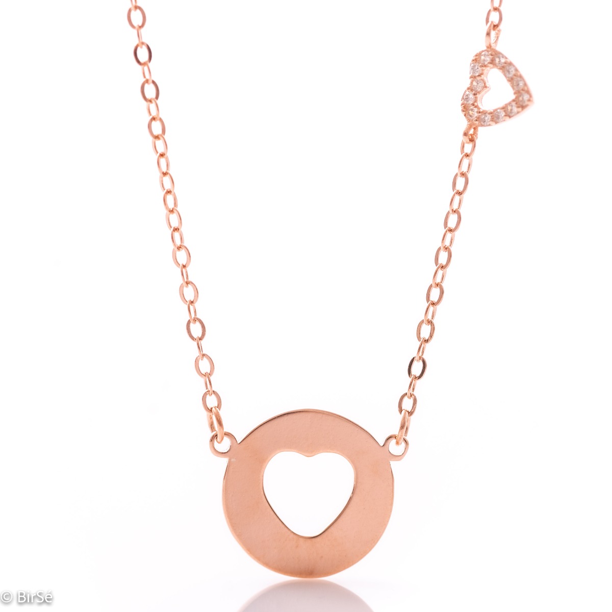 Modern women's necklace in soft rose silver with a round plate and a heart cut into it. As an addition, a small heart pendant with zircons is attached to the top of the chain.