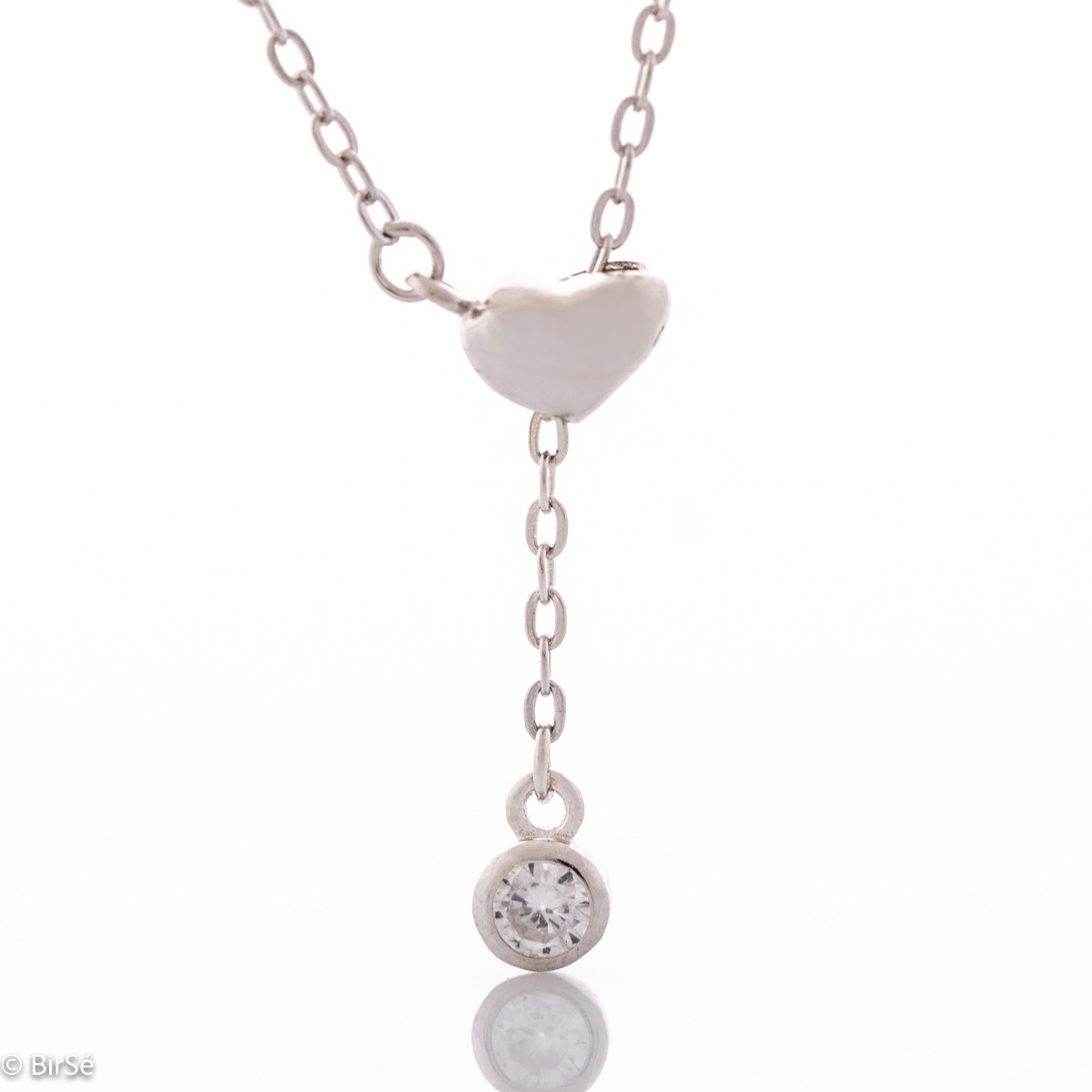 A simple silver necklace with a delicate chain, spectacularly threading through a beautiful heart of rhodium-plated silver and ending with a pendant of masterfully cut sparkling zircon.