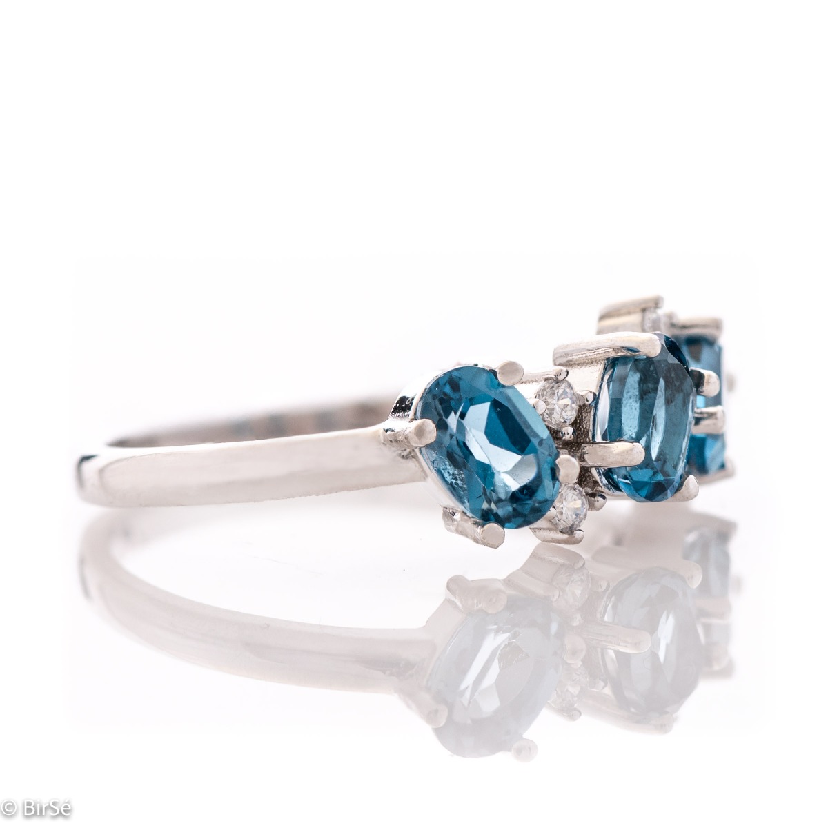 Sparkling ring with exquisite craftsmanship and delicate curves entirely in rhodium silver, a beautiful combination of asymmetric radiant natural London topaz stones complemented with sparkling zircons.