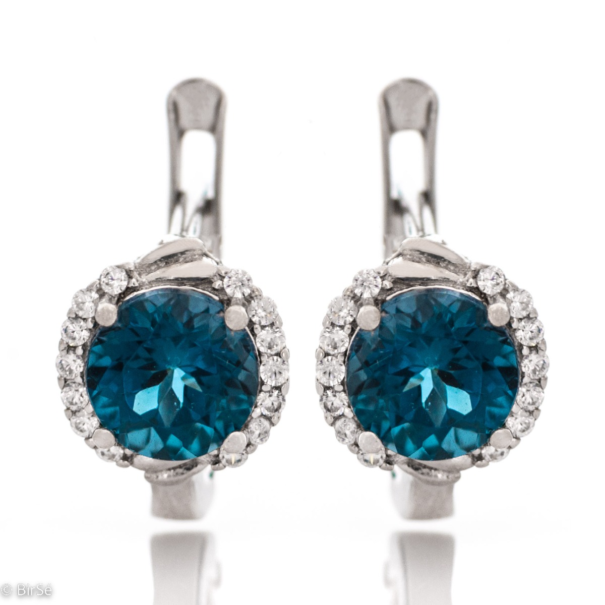 Magnificent earrings in delicate rhodium silver. A round shaped natural London topaz stone lies in the center surrounded by spectacular cubic zirconias.