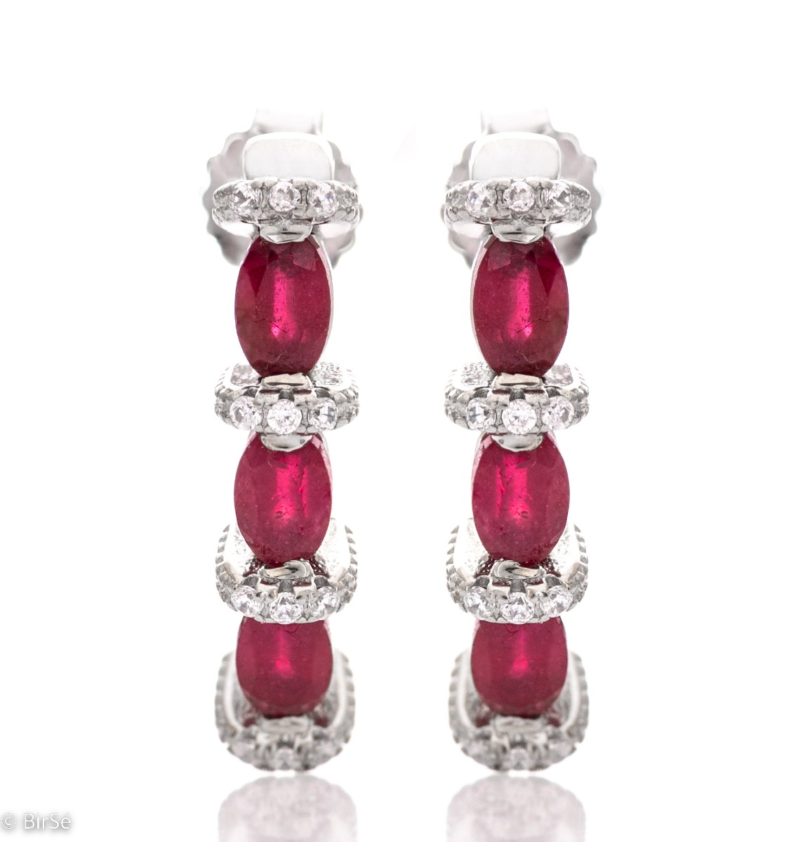 Elegant earrings made of rhodium silver and a magnificent ruby, delicately combined with zircons. A stylish design, successfully applied in a pendant and ring by the model.