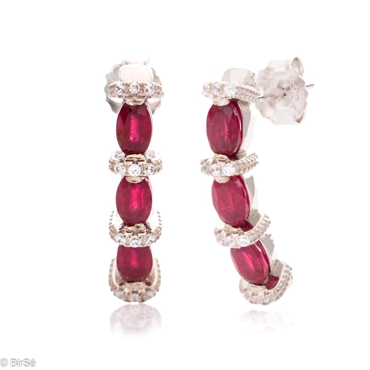 Elegant earrings made of rhodium silver and a magnificent ruby, delicately combined with zircons. A stylish design, successfully applied in a pendant and ring by the model.