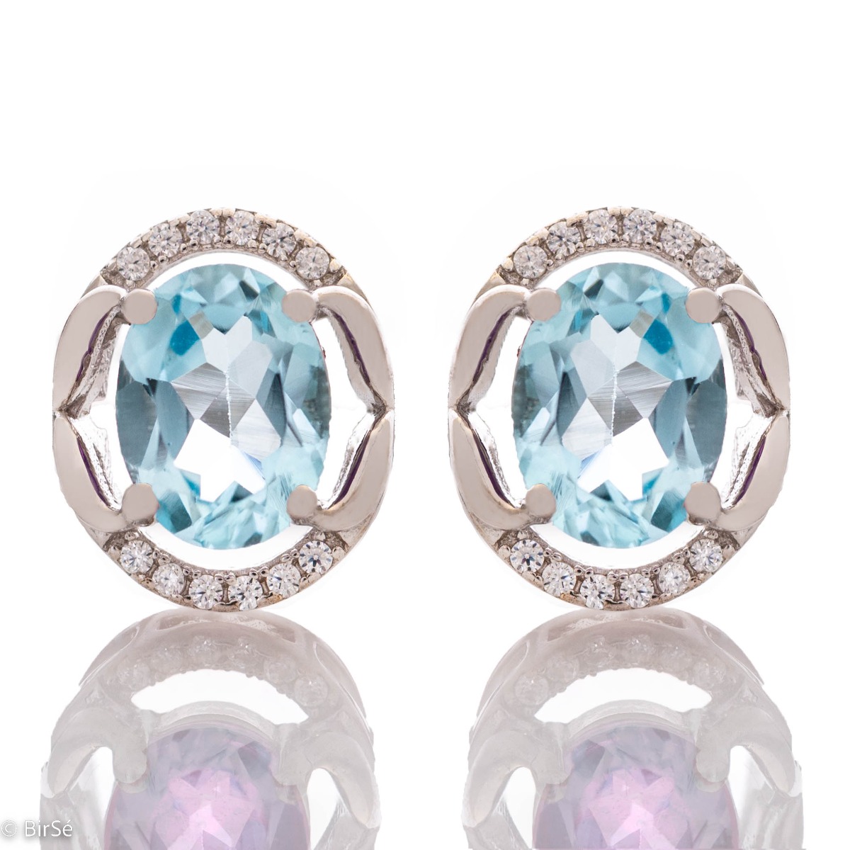 A royal vision - elegant silver earrings with a delicate design. Stylish composition made of fine combination of rhodium silver with sparkling zircon stones and exquisite blue topaz. In a lovely set with a ring from the model.