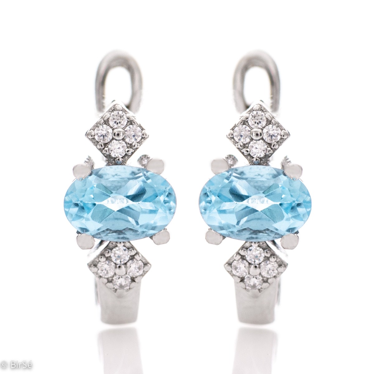 Extremely radiant ladies' English clasp earrings, combining the sparkle of delicate zircons with a natural blue topaz stone. Complemented with exquisite and fine workmanship entirely in beautiful rhodium-plated silver.