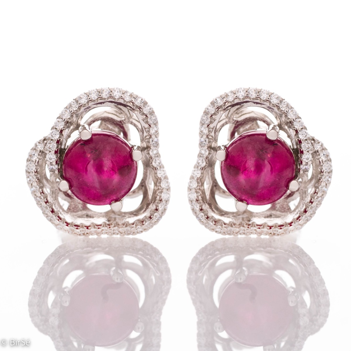 Sophisticated earrings with an exquisite flower-shaped pattern, painstakingly crafted from rhodium-plated silver, captivating ruby ​​and fine cubic zirconias. The set includes a pendant and a ring with the same lovely design.