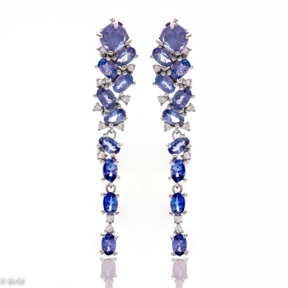 Elegant women's English clasp earrings, resembling a waterfall of numerous natural tanzanite stones, complemented by delicate zircons and a delicate rhodium-plated silver design. In an exclusive pendant and ring set.