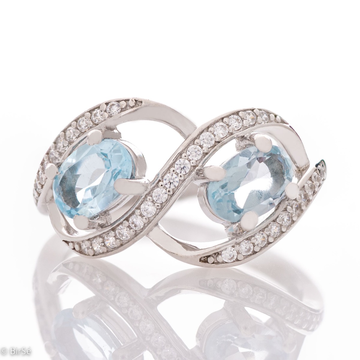 Ring with Exquisite Infinity of Rhodified Silver with Shining Zircons and Enchanted Blue Topaz 0,56 ct.