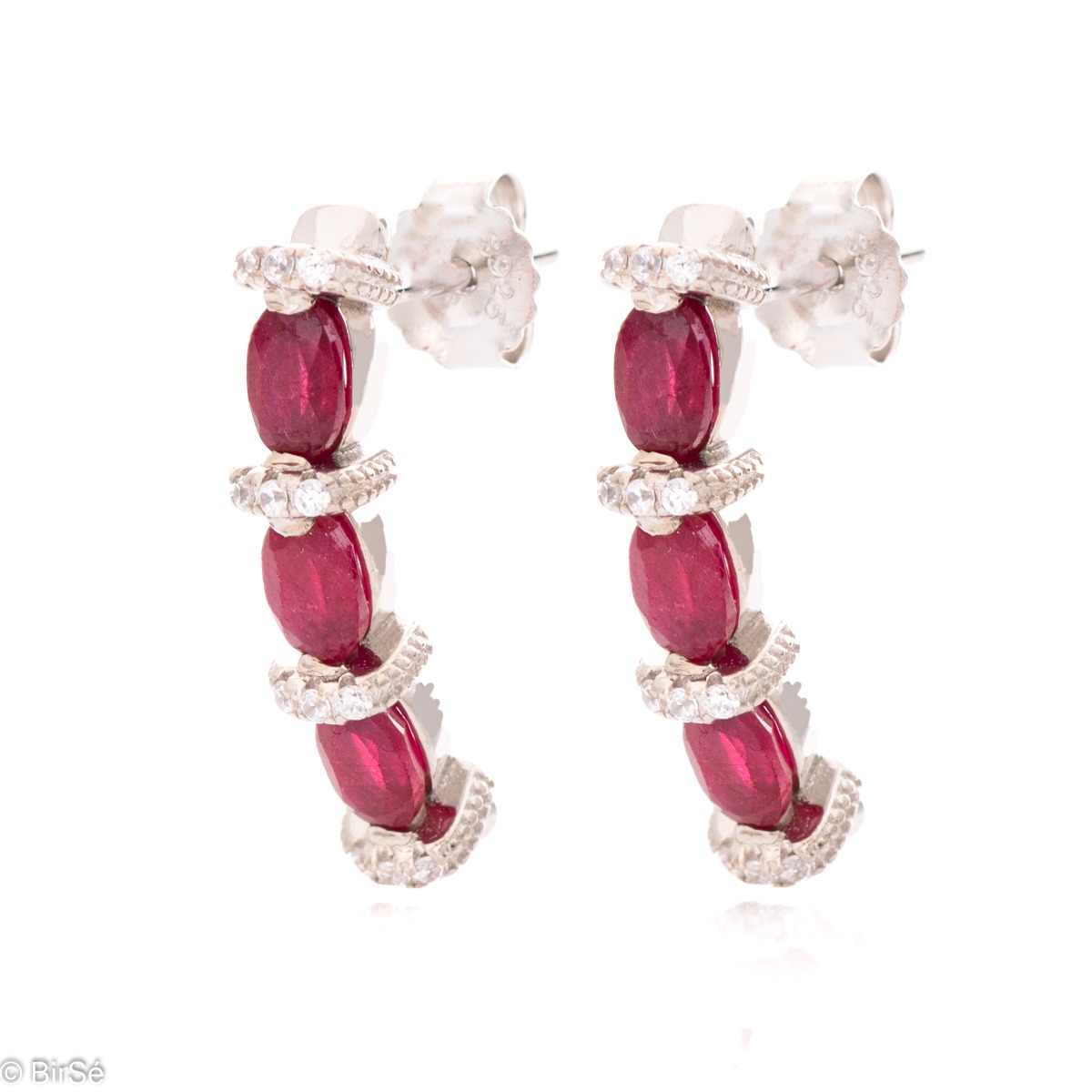 Elegant earrings made of rhodium silver and a magnificent ruby, delicately combined with zircons. A stylish design, successfully applied in a pendant and ring by the model.