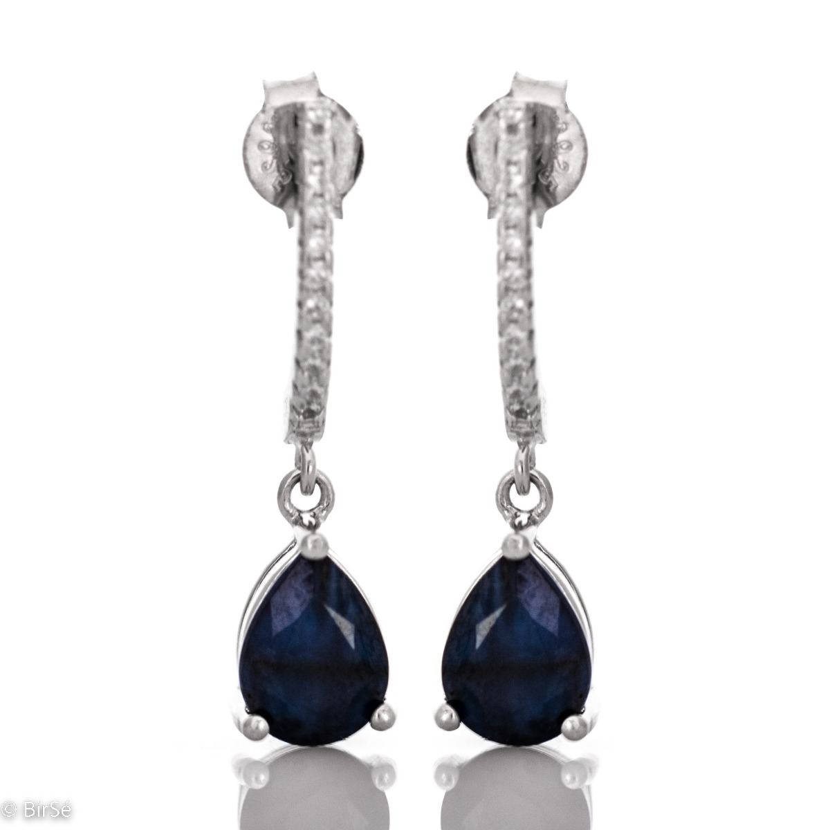 An elegant model of women's dangling earrings, entirely made of rhodium-plated silver. The natural drop-shaped sapphire and sparkling zircons add exceptional sophistication.