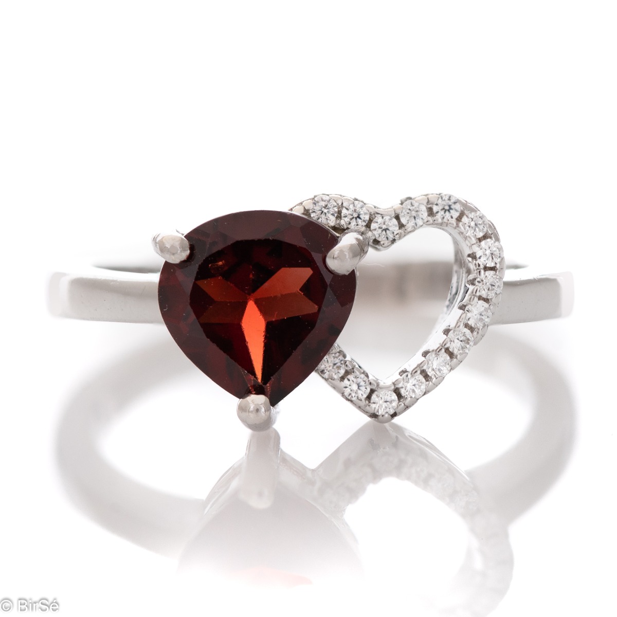 A spectacular ring made of a fine combination of rhodium-plated silver and stunning cubic zirconia stones, elegantly covering a beautiful heart. An enchanted natural garnet stone is gently nestled against the heart. The jewel is part of a set of dangling 