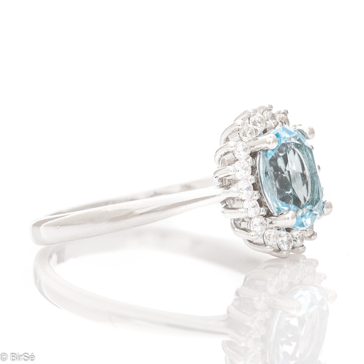 A radiant women's ring with delicate craftsmanship entirely made of rhodium-plated silver, complemented by a unique natural blue topaz stone and the sparkle of fine zircons. Part of an exclusive set with a delicate pendant and earrings.