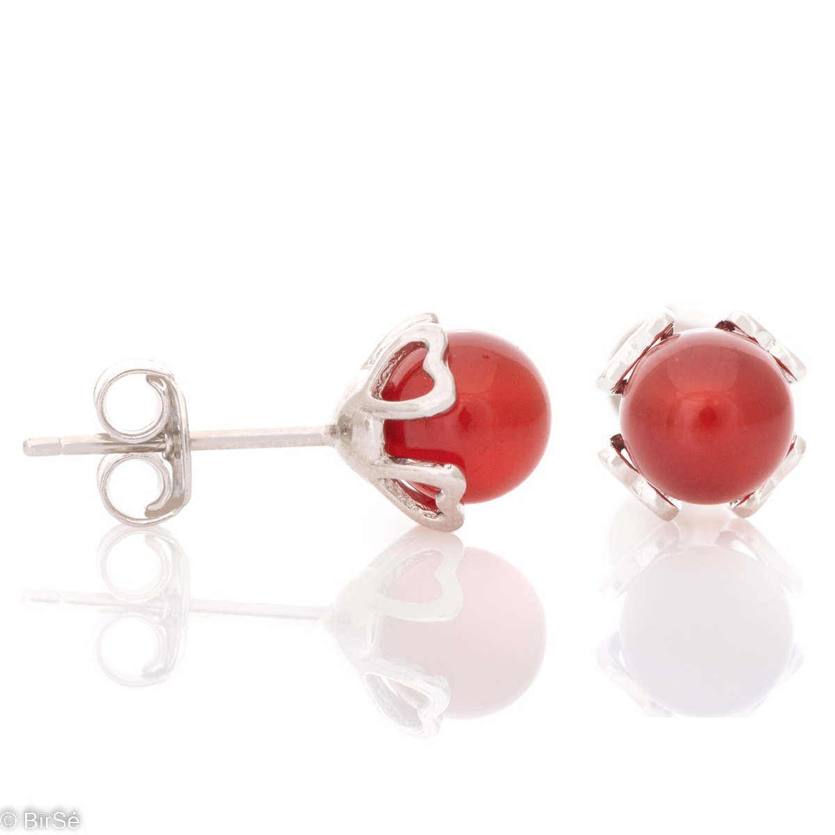 Charming women's earrings, with a heart-shaped case entirely made of rhodium-plated silver. In the middle is a red ball made of synthetic stone. The earrings have a classic pin fastening.