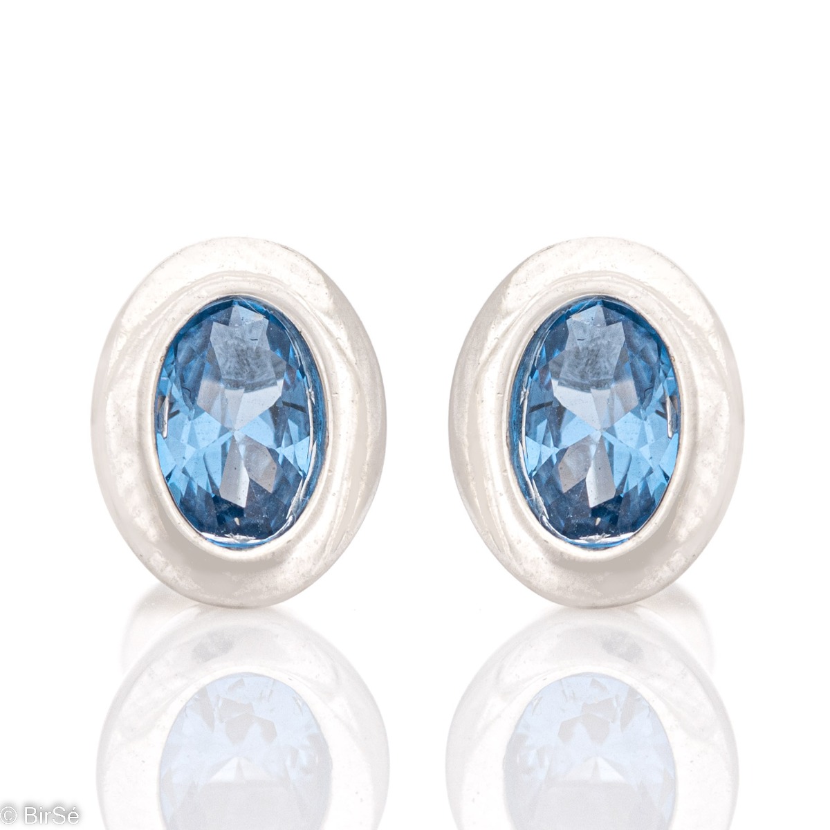 Stylishly crafted elegant women's earrings made of fine rhodium silver, enclosing a captivating blue zircon. The earrings are fastened with a pin, for greater convenience and security. In a charming pendant and ring set with the same look.