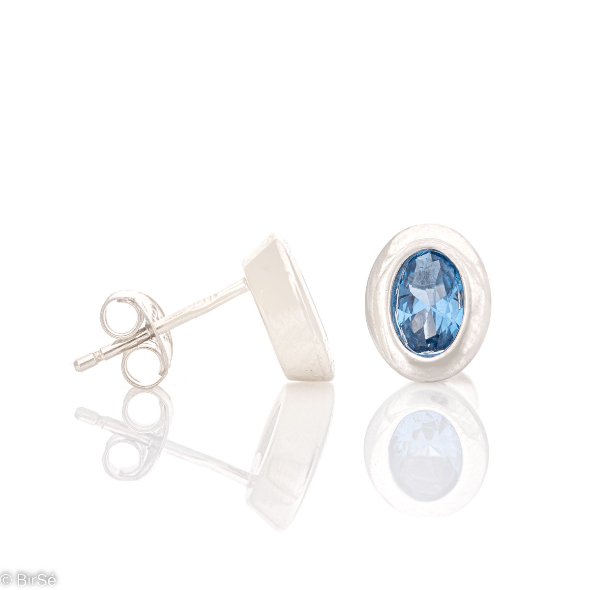 Stylishly crafted elegant women's earrings made of fine rhodium silver, enclosing a captivating blue zircon. The earrings are fastened with a pin, for greater convenience and security. In a charming pendant and ring set with the same look.