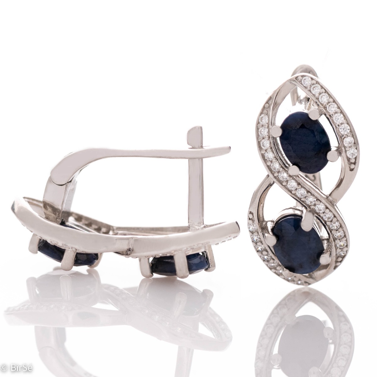 Stunning earrings beautifully crafted in rhodium-plated sterling silver with an infinity shape, exquisitely embellished with sparkling cubic zirconias surrounding magnetic sapphires. Complete with a ring of the same design.