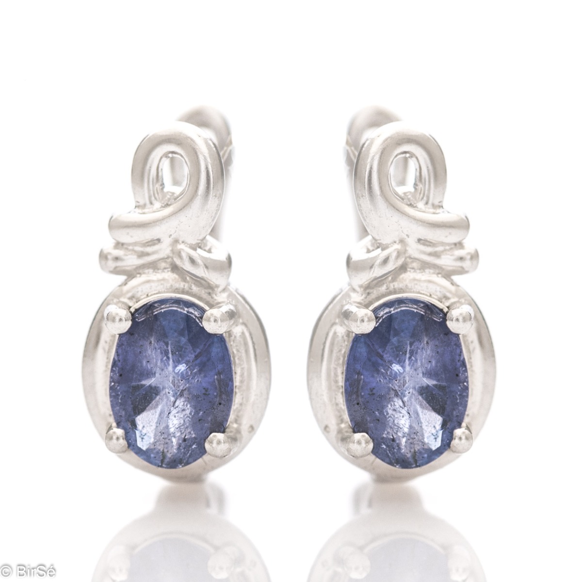 Exquisite ladies' earrings with an English clasp and a gentle interweaving of shiny rhodium silver with a magnetic natural tanzanite stone. They come in an elegant ring and pendant set.