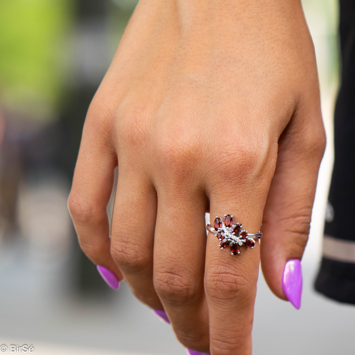 Delicately elegant silver ring with a charming look and innovative design. Stylish craftsmanship from a fine combination of rhodium-plated silver with charming natural garnet stones and delicate zircons.