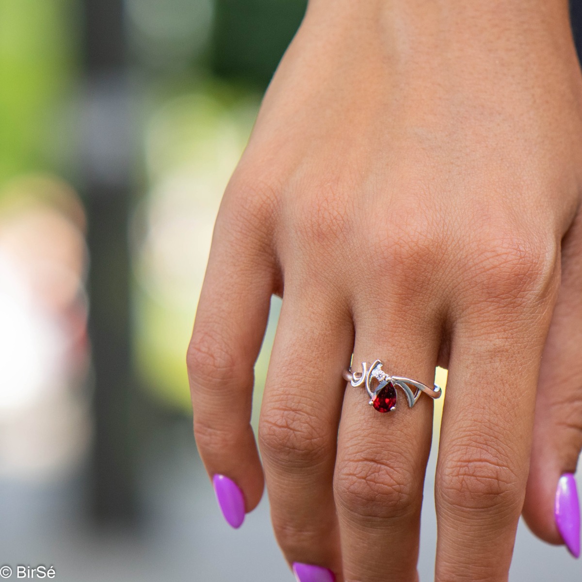 Elegant ladies' ring with subtle curves and made entirely of beautiful rhodium-plated silver, complemented by a radiant natural garnet, in a delicate teardrop shape and a fine zircon. In an exclusive set with a pendant and earrings.