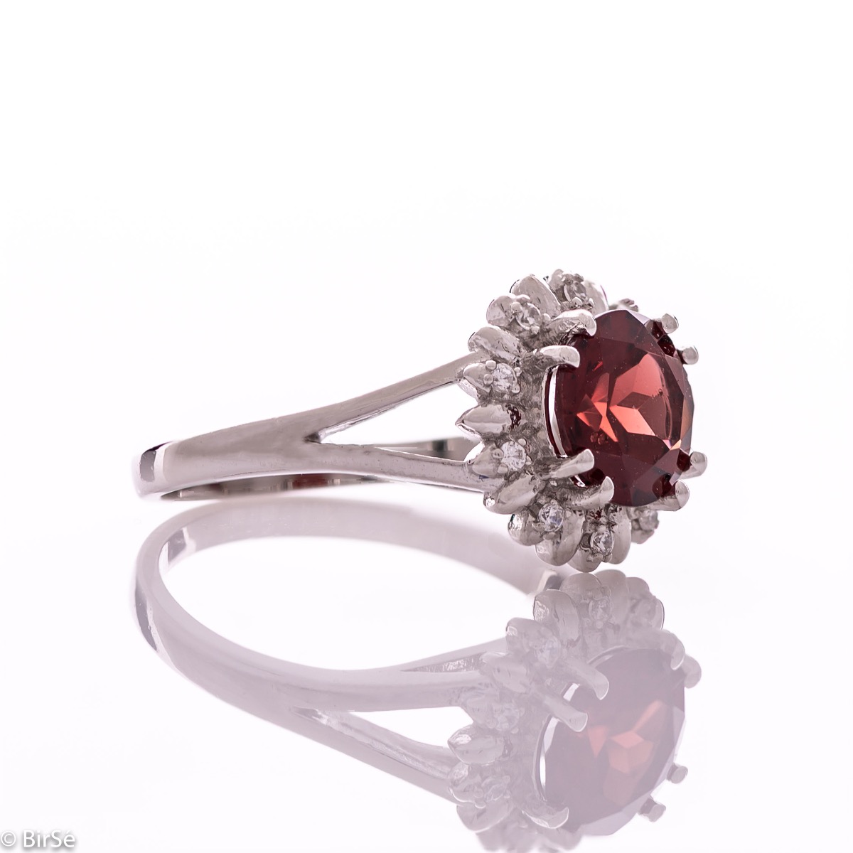 An elegant women's ring with precise craftsmanship combining delicate rhodium-plated silver with a radiant natural garnet surrounded by sparkling zircons. Can be combined with earrings and pendant of the same model.