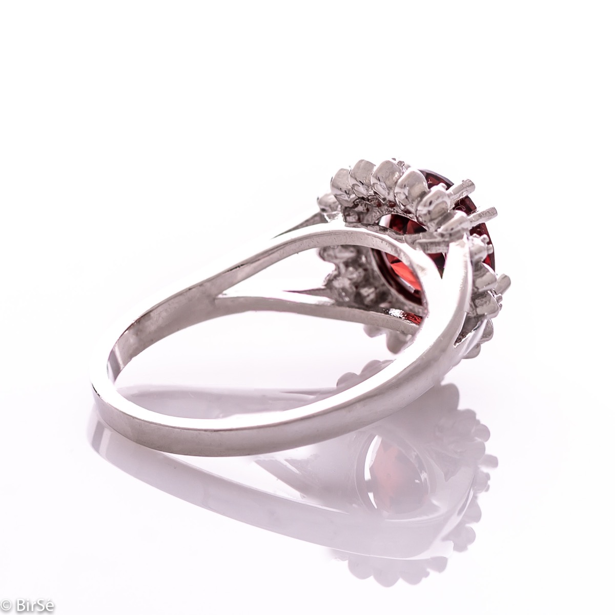 An elegant women's ring with precise craftsmanship combining delicate rhodium-plated silver with a radiant natural garnet surrounded by sparkling zircons. Can be combined with earrings and pendant of the same model.