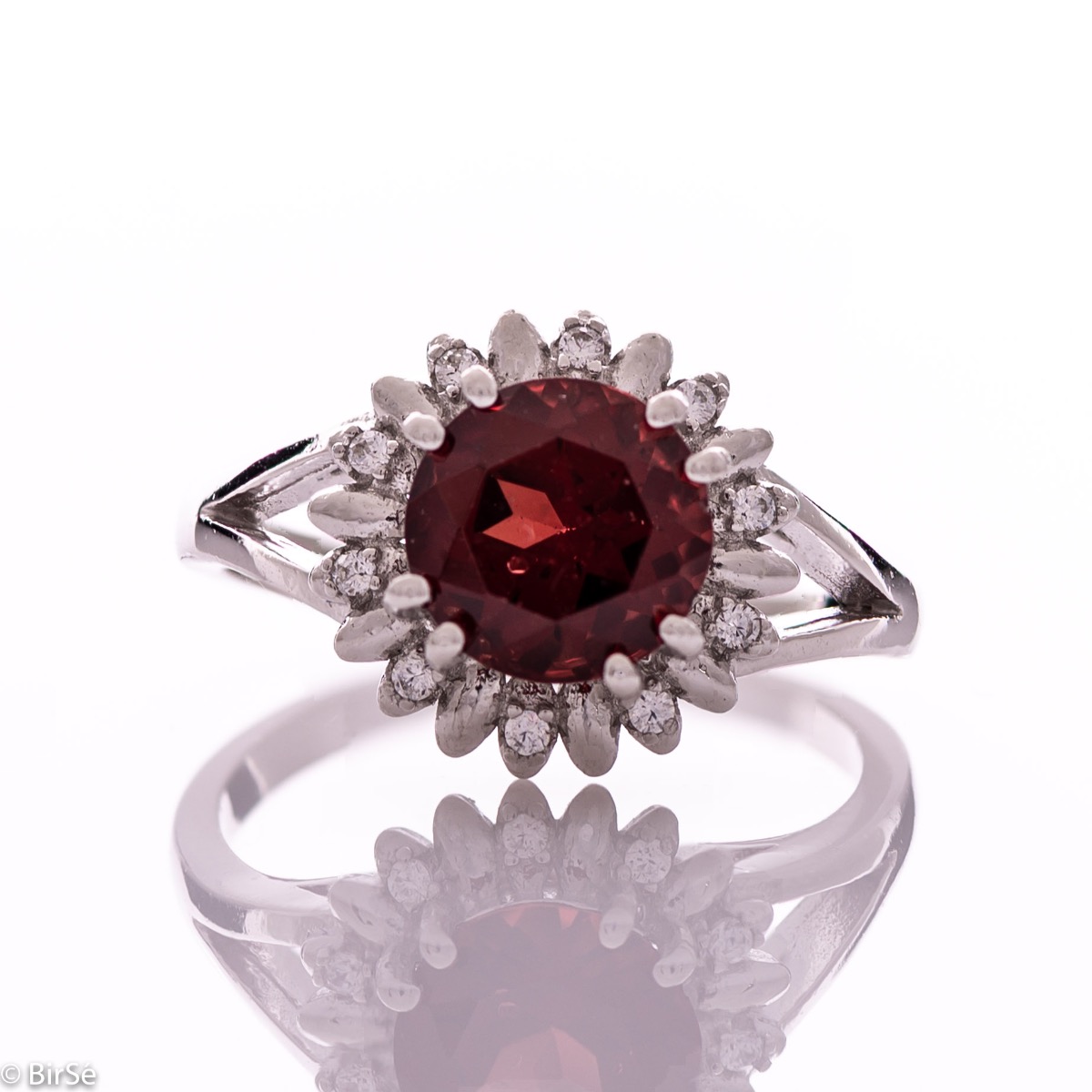 An elegant women's ring with precise craftsmanship combining delicate rhodium-plated silver with a radiant natural garnet surrounded by sparkling zircons. Can be combined with earrings and pendant of the same model.