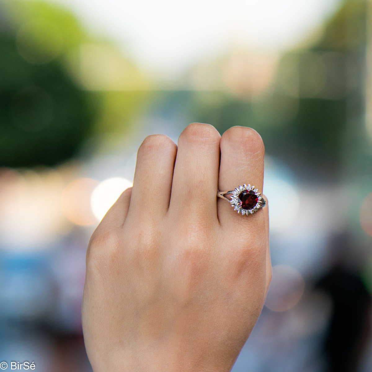 An elegant women's ring with precise craftsmanship combining delicate rhodium-plated silver with a radiant natural garnet surrounded by sparkling zircons. Can be combined with earrings and pendant of the same model.