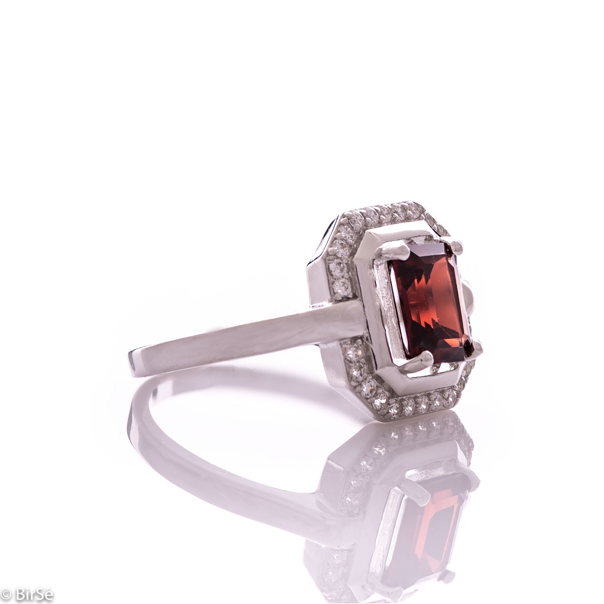 An elegant women's ring made of rhodium-plated silver, combined with the gentle glow of a natural garnet stone, surrounded by sparkling zircons. It can be combined with a pendant and earrings of the same model.