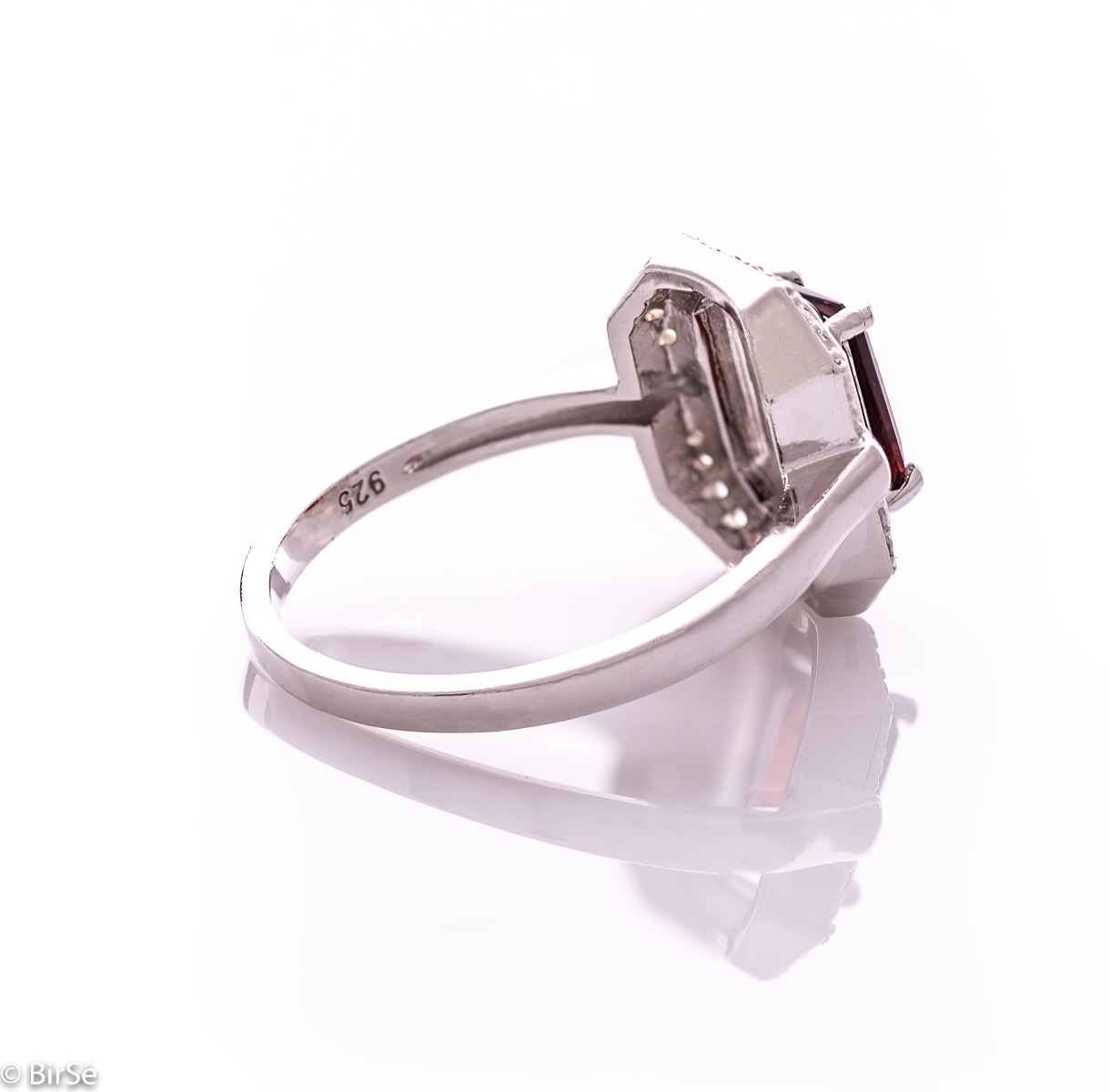 An elegant women's ring made of rhodium-plated silver, combined with the gentle glow of a natural garnet stone, surrounded by sparkling zircons. It can be combined with a pendant and earrings of the same model.