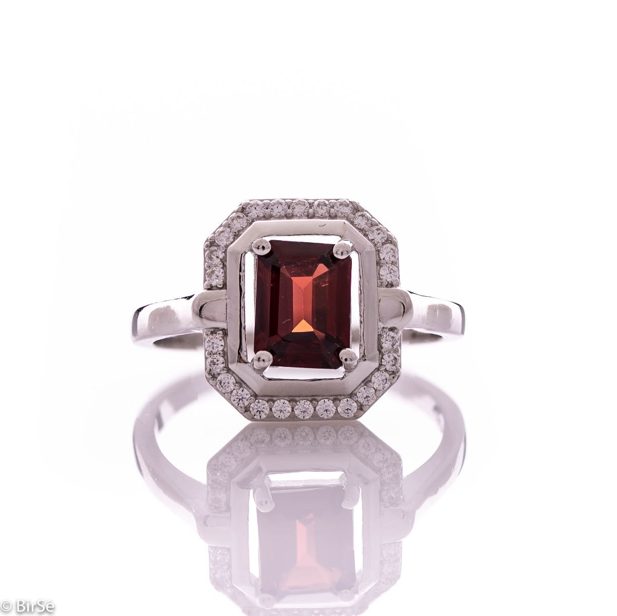 An elegant women's ring made of rhodium-plated silver, combined with the gentle glow of a natural garnet stone, surrounded by sparkling zircons. It can be combined with a pendant and earrings of the same model.