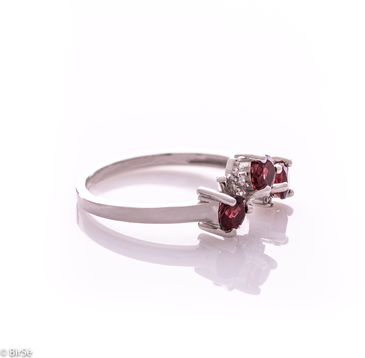 An elegant women's ring with a charming design, combining three radiant natural garnet stones with sparkling zircons and precision craftsmanship entirely in rhodium-plated silver. Can be combined with earrings and pendant of the same model.