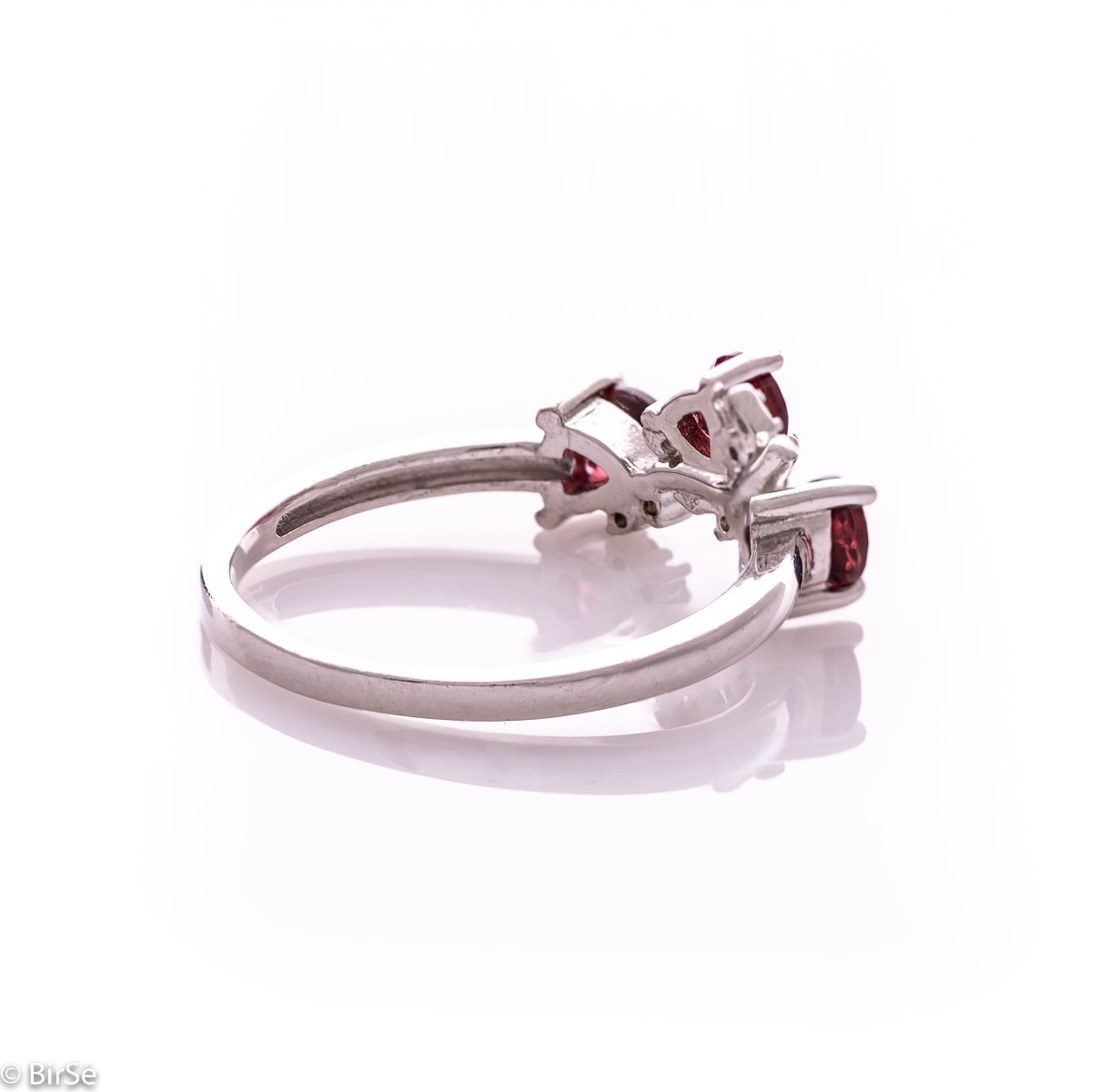 An elegant women's ring with a charming design, combining three radiant natural garnet stones with sparkling zircons and precision craftsmanship entirely in rhodium-plated silver. Can be combined with earrings and pendant of the same model.