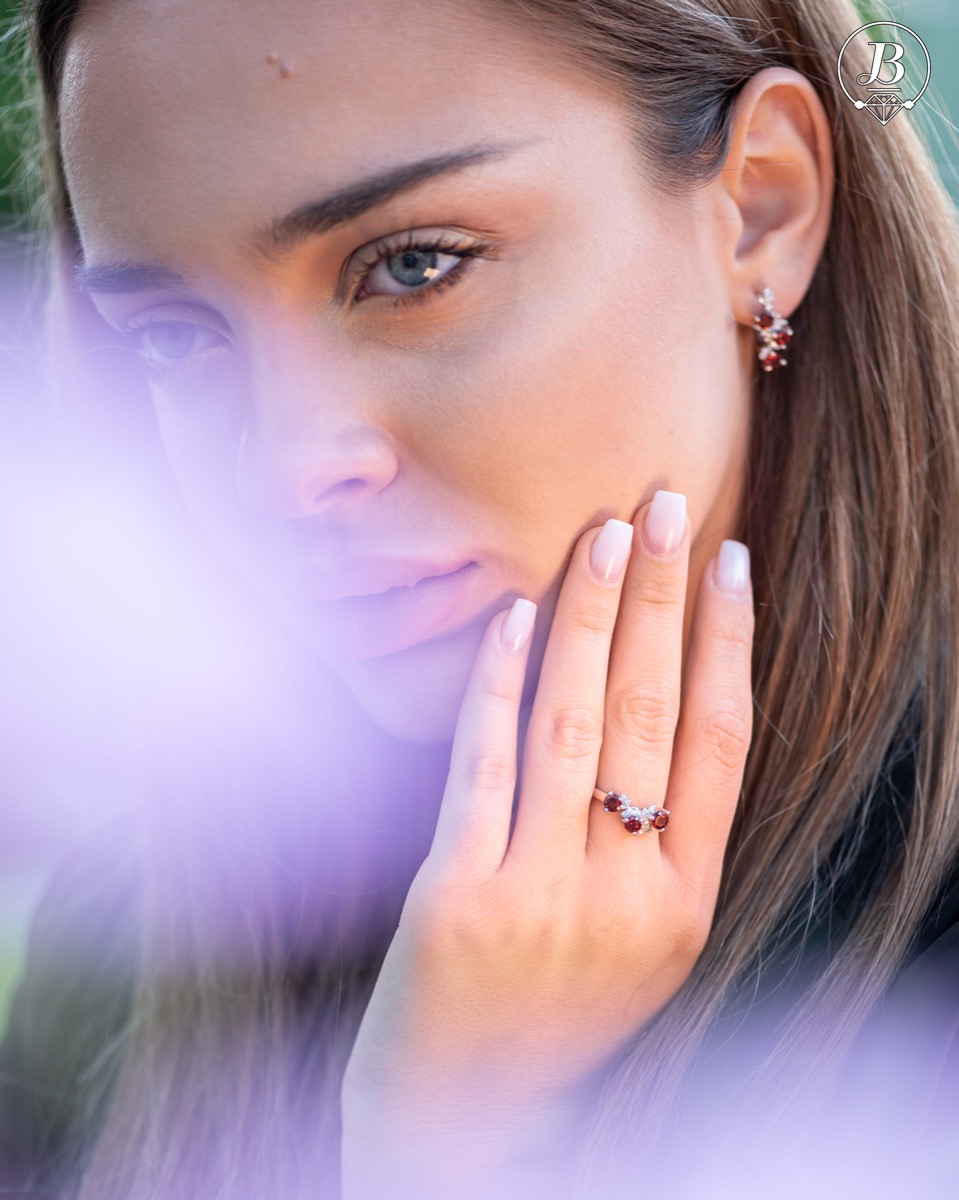 An elegant women's ring with a charming design, combining three radiant natural garnet stones with sparkling zircons and precision craftsmanship entirely in rhodium-plated silver. Can be combined with earrings and pendant of the same model.