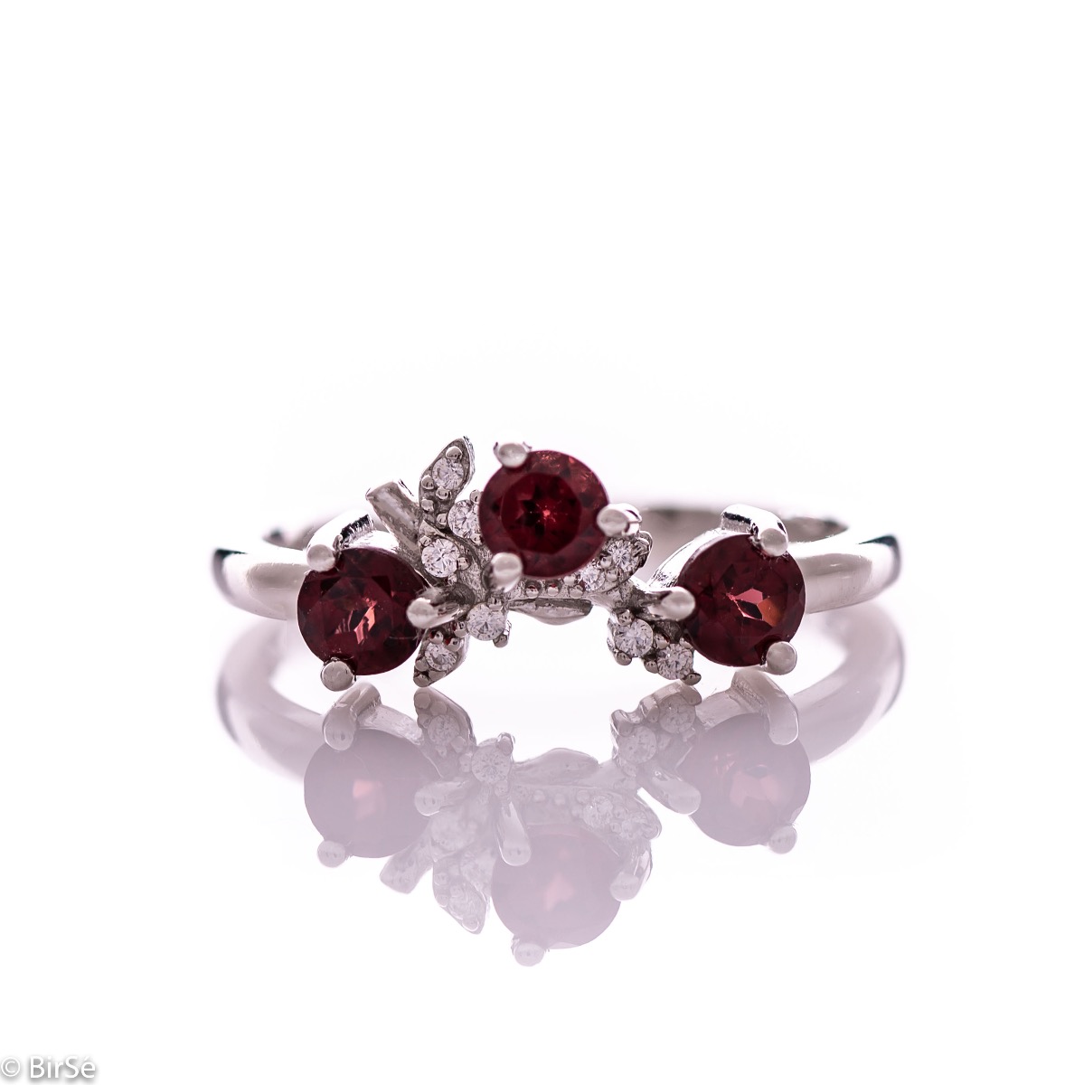 An elegant women's ring with a charming design, combining three radiant natural garnet stones with sparkling zircons and precision craftsmanship entirely in rhodium-plated silver. Can be combined with earrings and pendant of the same model.